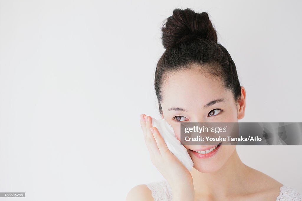 Young woman putting face-wash foam