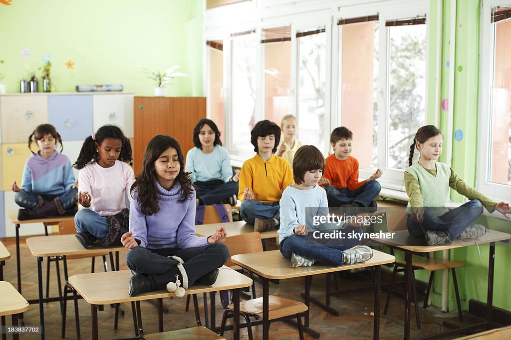 Pupille praticare yoga in classe.