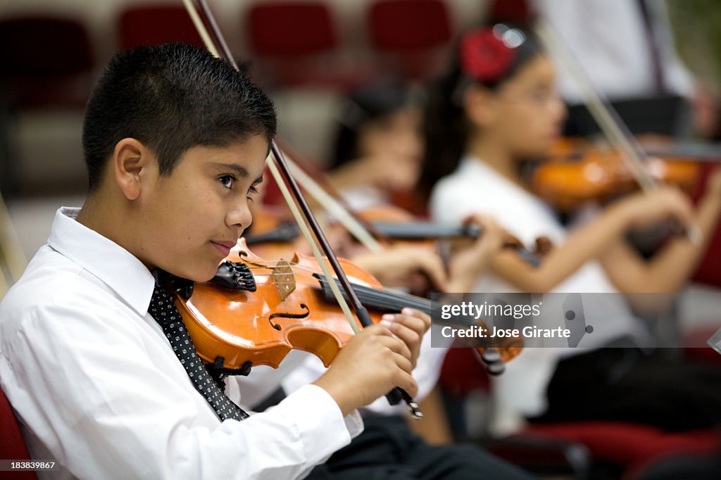 A young boy plays violin and stares outward