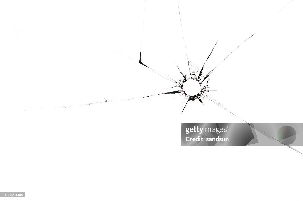 A single bullet whole through glass on a white background