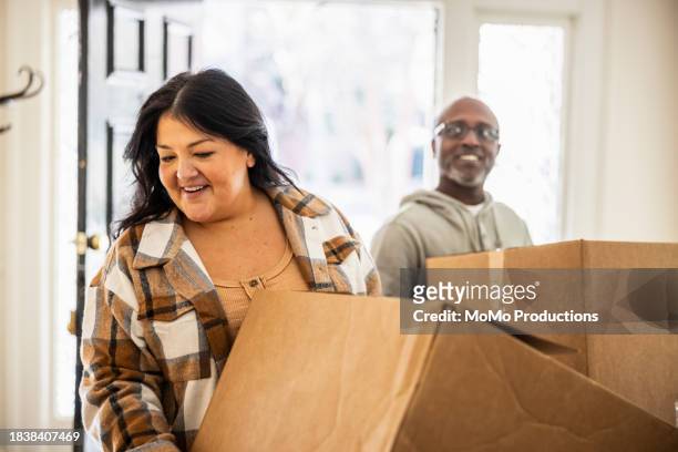 interracial couple bringing moving boxes into home - man with moving boxes authentic stockfoto's en -beelden