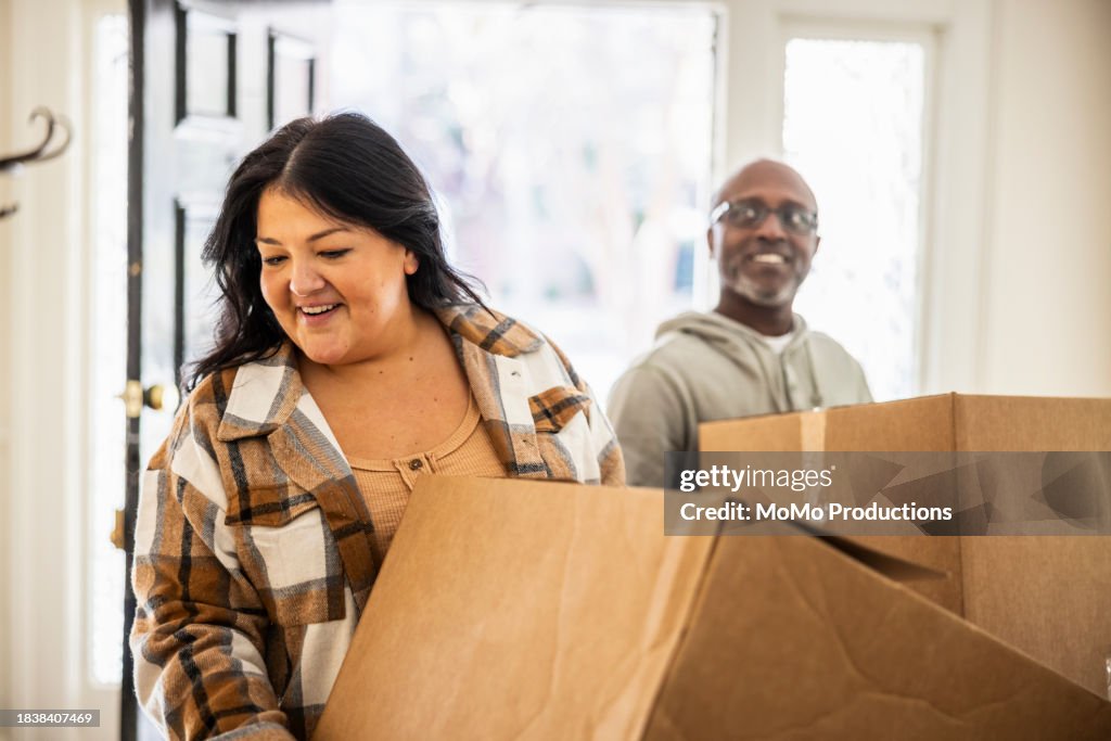 Interracial couple bringing moving boxes into home