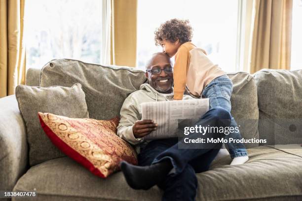 father reading newspaper while toddler climbs on him - reportage home stock pictures, royalty-free photos & images