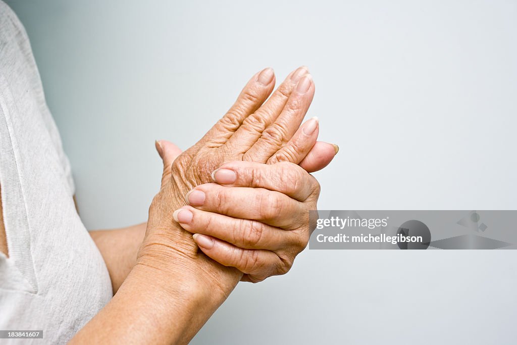 Elderly woman grasping arthritic hands