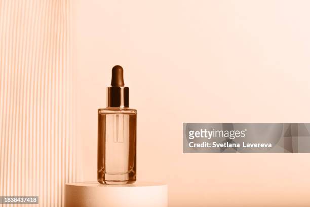 glass dropper bottle with a pippette with black rubber tip on the beautiful beige background. nature skin concept. organic spa cosmetics.  demonstrating pantone color trend 2024 - peach fuzz. trendy colours. - mottled skin 個照片及圖片檔