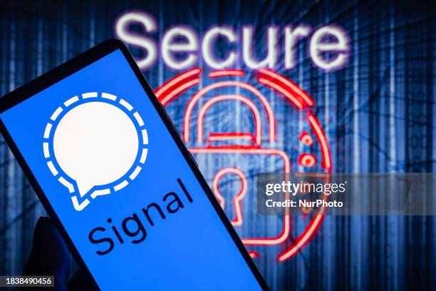 The Signal messenger logo is being displayed on a smartphone with symbols of security and a lock in the background, in this photo illustration in...