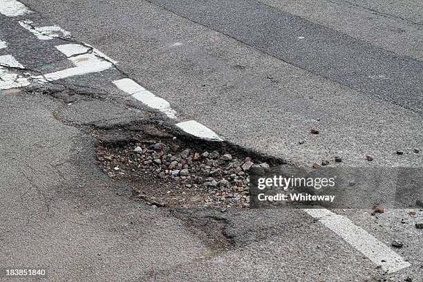 bad repair pothole in road t-junction suffers frost damage - gat stockfoto's en -beelden