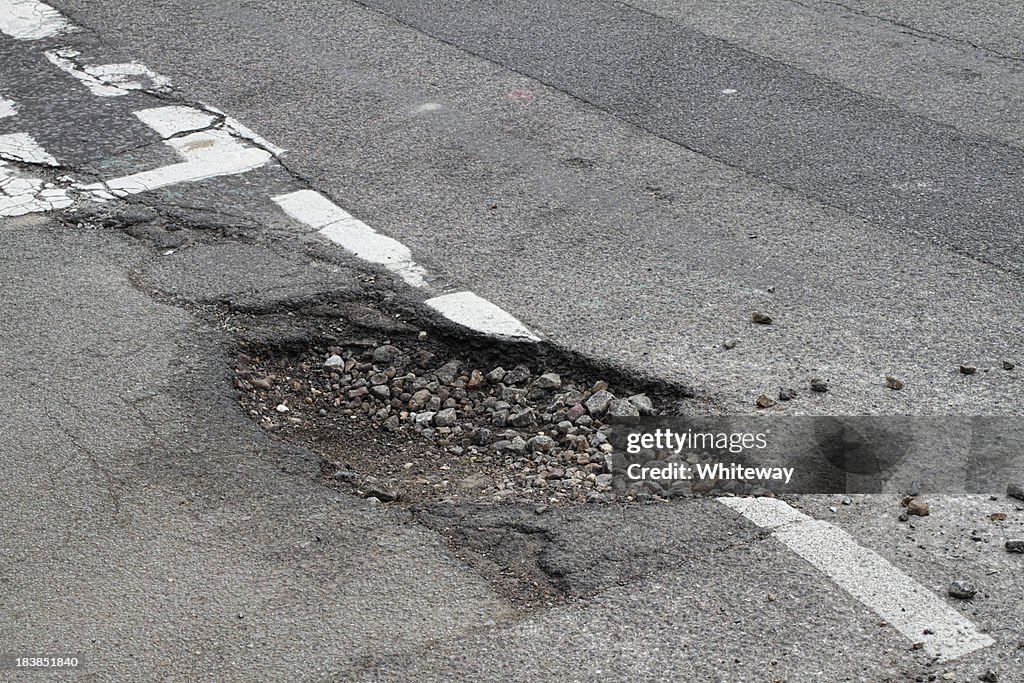 Bad repair pothole in road T-junction suffers frost damage