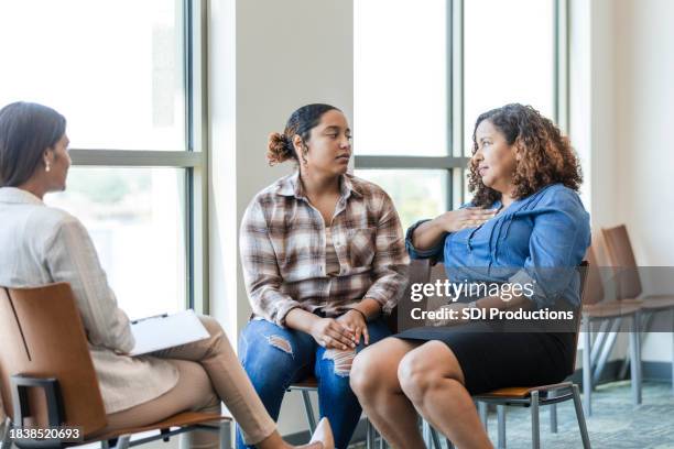 mother gestures while speaking to her daughter in counseling - emotional support stock pictures, royalty-free photos & images