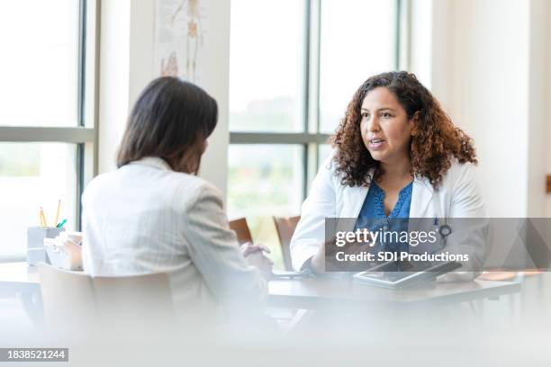 female doctor gestures while talking to her patient - medisch document stockfoto's en -beelden