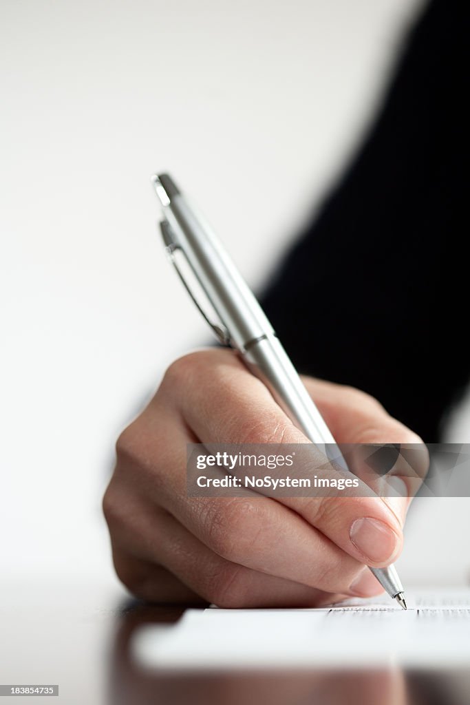 Close-up of hand writing with a silver ballpoint pen