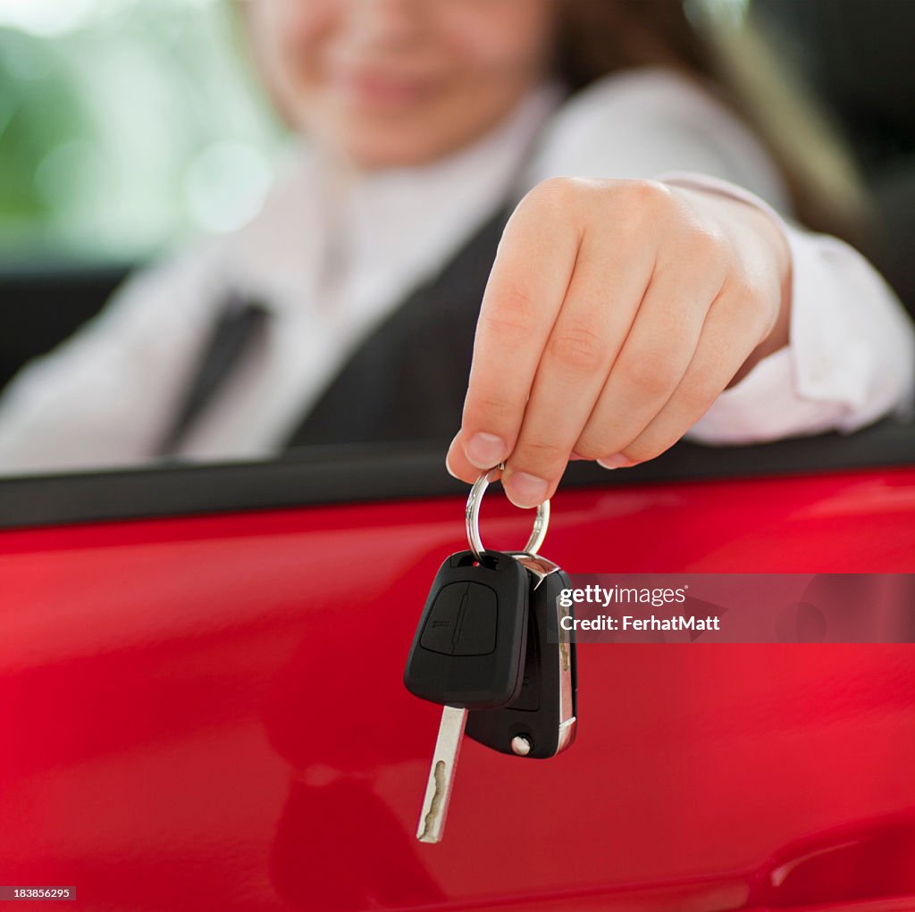 Woman seated in a car holding keys out the window