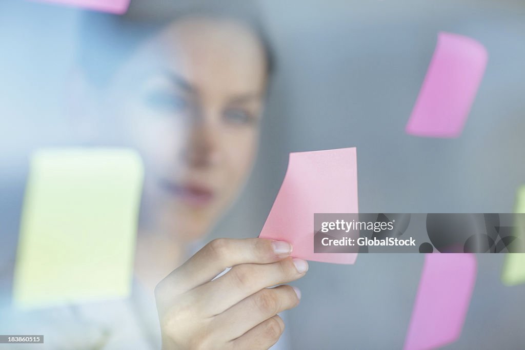 Business woman taking out a note from the window