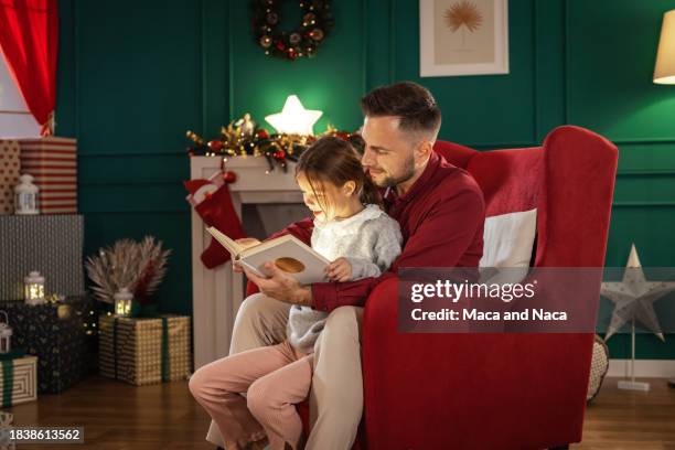 vater liest seiner tochter in der weihnachtszeit ein buch vor - märchen stock-fotos und bilder