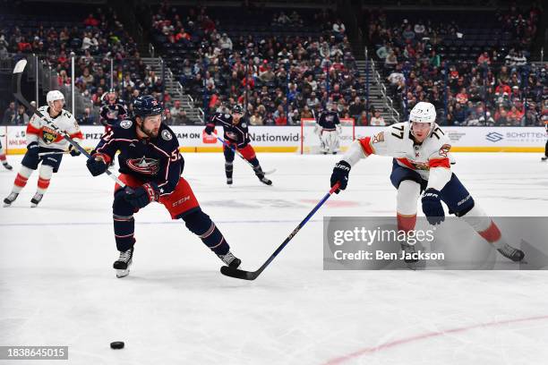 Emil Bemstrom of the Columbus Blue Jackets and Niko Mikkola of the Florida Panthers skate after a loose puck during the first period of a game at...