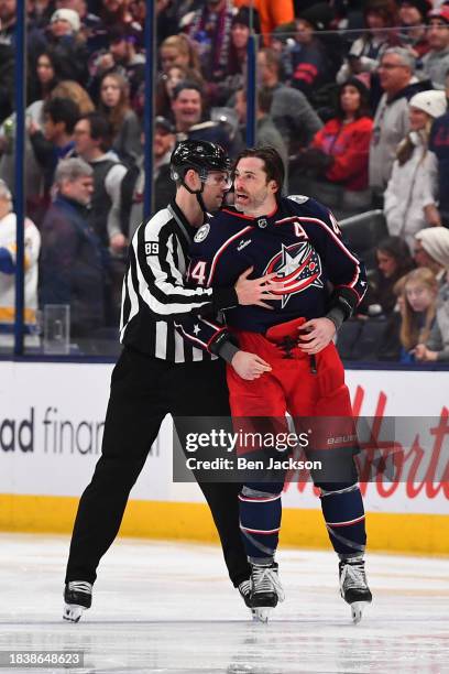 Erik Gudbranson of the Columbus Blue Jackets is escorted to the bench by linesmen Joe Mahon during the third period of a game against the Florida...