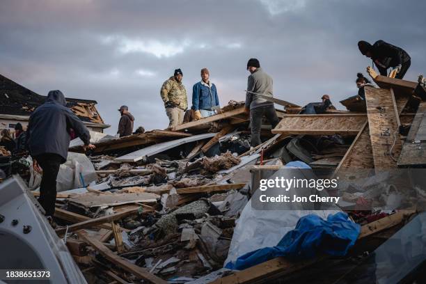 Residents and visitors work to clear debris in search of pets and belongings of a destroyed home in the aftermath of a tornado on December 10, 2023...