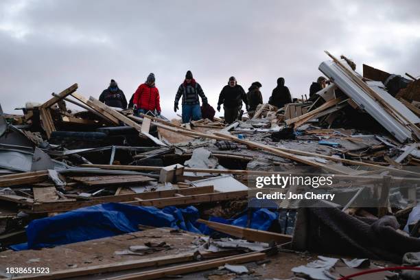Residents and visitors work to clear debris in search of pets and belongings of a destroyed home in the aftermath of a tornado on December 10, 2023...