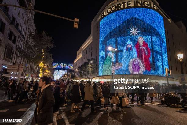 Crowd of people is seen passing in front of the traditional Christmas decorations of the emblematic El Corte Inglés shopping center. The city of...