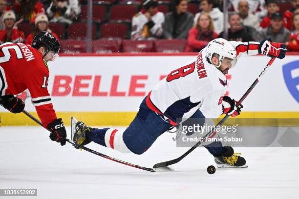 Alex Ovechkin of the Washington Capitals is tripped up by Joey Anderson of the Chicago Blackhawks while attempting a shot on goal in the third period...