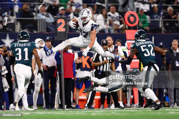 Jake Ferguson of the Dallas Cowboys hurdles Kelee Ringo of the Philadelphia Eagles during the fourth quarter of an NFL football game at AT&T Stadium...