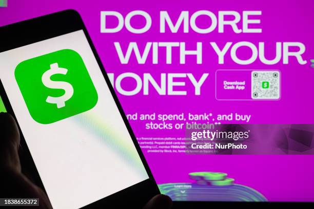 The Cash App online banking logo is being displayed on a smartphone with the Cash App web page visible in the background, in this photo illustration...