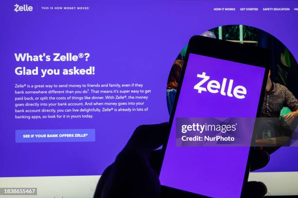 The Zelle online banking logo is being displayed on a smartphone with the Zelle web page visible in the background, in this photo illustration, in...