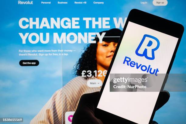 The Revolut online banking logo is being displayed on a smartphone with the Revolut web page visible in the background, in this photo illustration,...