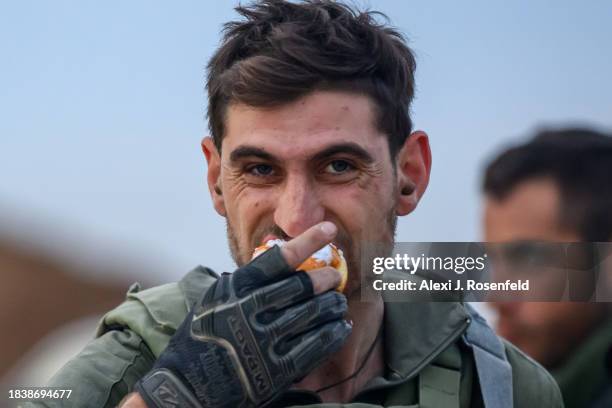 Soldier's eats a sufgania ahead of lighting hanukah candles on the first night of Hanukkah near the Gaza border on December 07, 2023 in Southern...