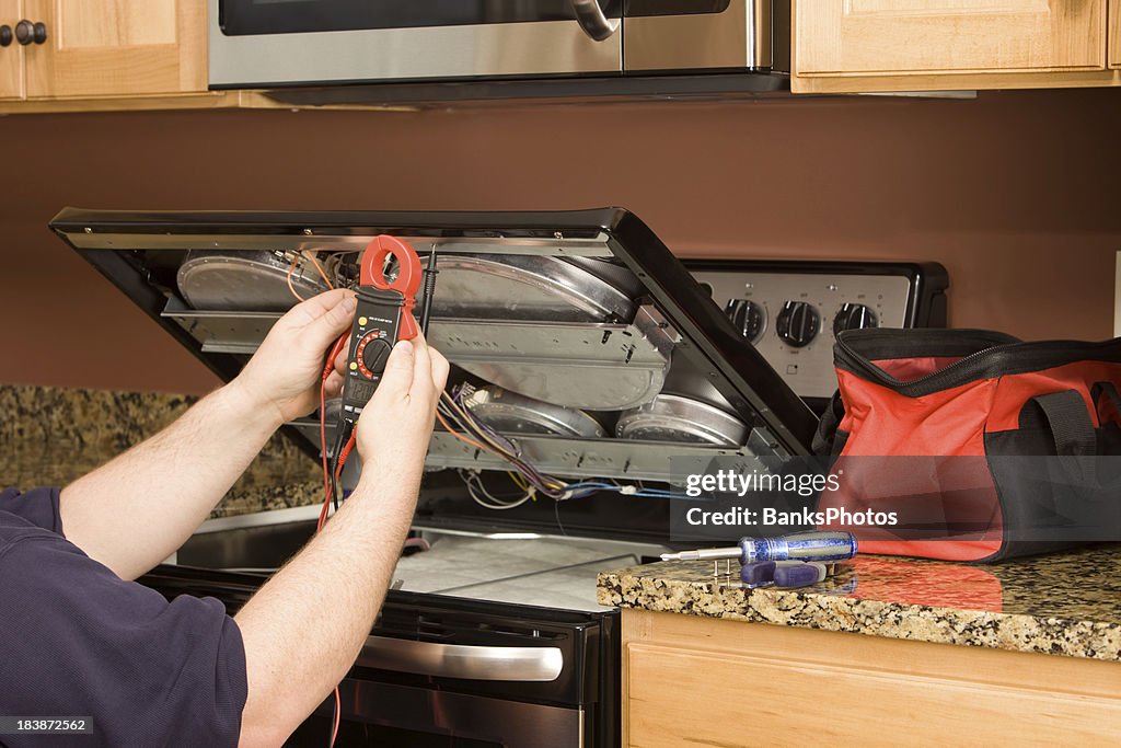 Appliance Repairman Using Multimeter on a Kitchen Range