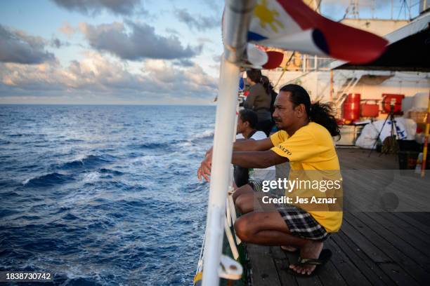 Filipino volunteers looks at the horizon for sightings of Chinese vessels onboard a Filipino ship on a resupply mission to the communities and...