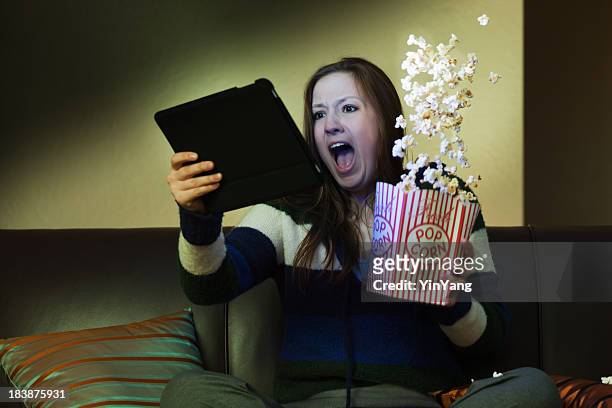 tablet computer entertainment, watching scary movie screaming with popcorn - surprised woman looking at tablet stock pictures, royalty-free photos & images