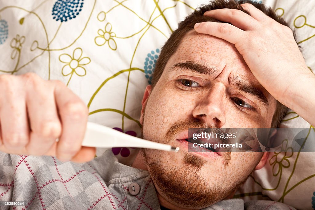 Homem deitada na cama com seu febre