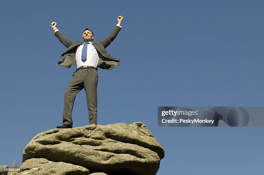 Businessman Celebrates Victory on Rocky Mountaintop