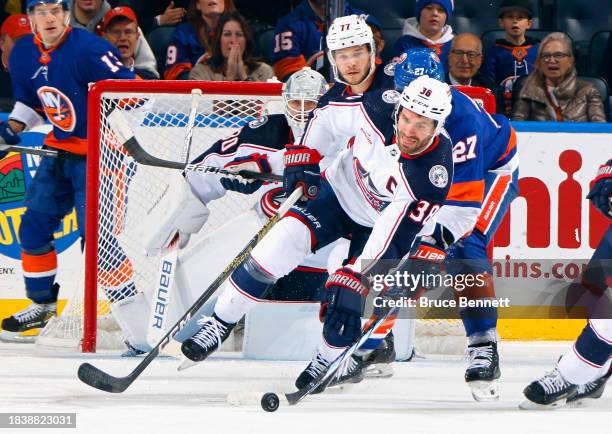 Anders Lee of the New York Islanders checks Boone Jenner of the Columbus Blue Jackets during the first period at UBS Arena on December 07, 2023 in...