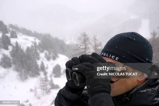 Border police officer of the DCPAF uses binocular lenses in search for illegal migrants on the French side of the border with Italy, in Montgenevre,...