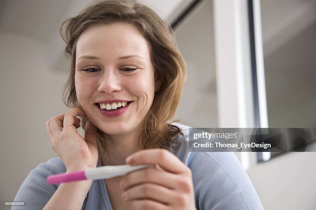 Young Woman Smiling at a Pregnancy Test