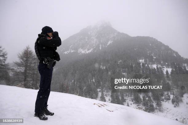 French gendarme uses binocular lenses in search for illegal migrants on the French side of the border with Italy, in Montgenevre, in the French Alps,...