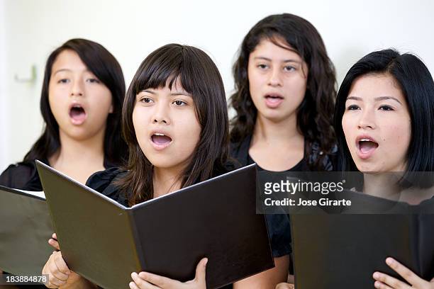 female choir singing while holding open music books - caroler stock pictures, royalty-free photos & images