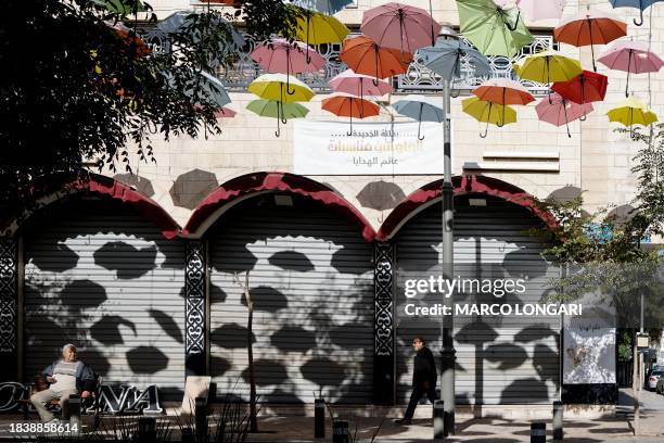 Man walks past shuttered shops during a general strike in solidarity with Gaza, in east Jerusalem on December 11 amid continuing battles between...