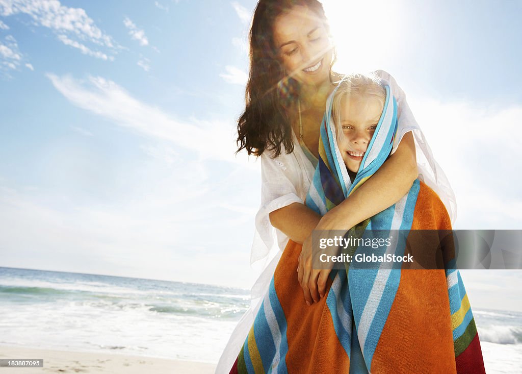 Mother covering daughter with towel on the beach