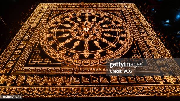 Aerial view of butter lamps lit on the square in front of the Puning Temple, also known as the Big Buddha Temple, at night to celebrate Butter Lamp...