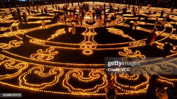 Aerial view of butter lamps lit on the square in front of the Puning Temple, also known as the Big Buddha Temple, at night to celebrate Butter Lamp...