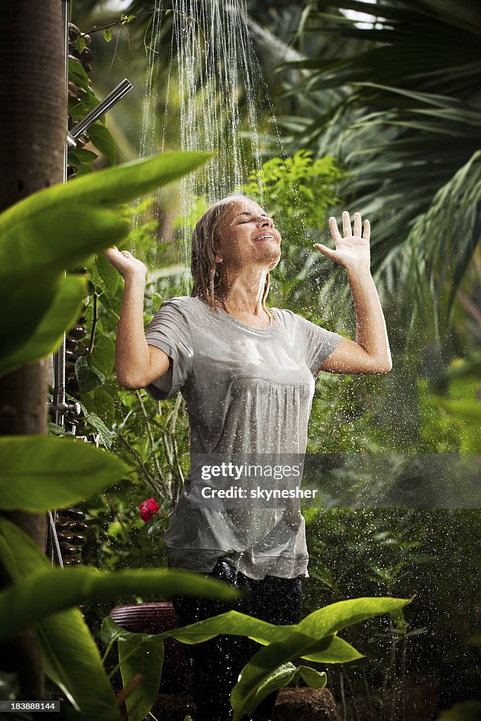 Cheerful woman having fun in the jungle during tropical rain.