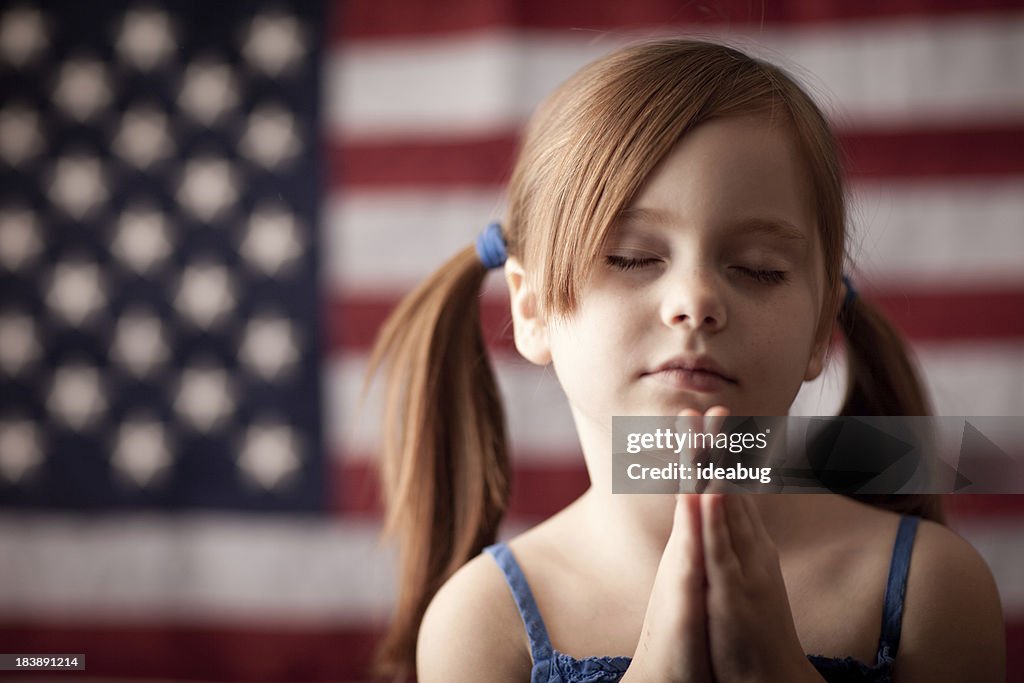 Jovem Menina Dobrar as mãos e rezar com Bandeira dos Estados Unidos da América