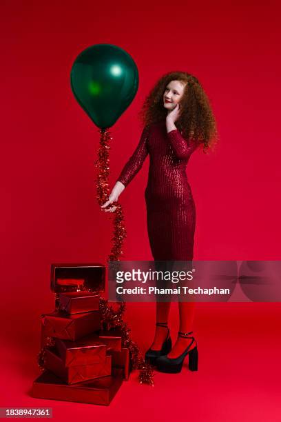 girl wearing red dress holding balloon on plain background - form fitted dress stock pictures, royalty-free photos & images
