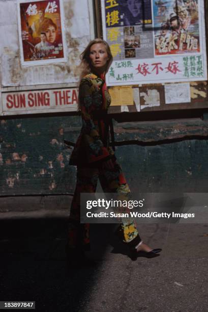 Portrait of an unidentified model dressed in a two-piece, print trouser suit as she walks on the streets of Manhattan's Chinatown, New York, New...