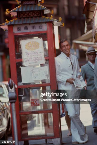 Portrait of German-born American fashion designer John Weitz dressed in one of his designs, a white suit with toggle fasterners, as he poses beside a...