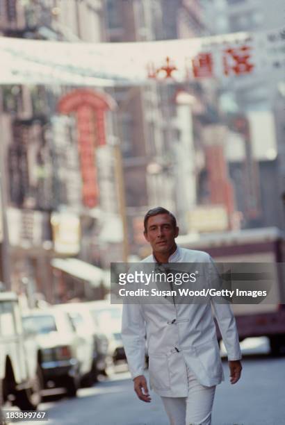 Portrait of German-born American fashion designer John Weitz dressed in one of his designs, a white suit with toggle fasterners, as he poses on the...
