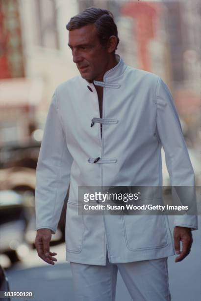 Portrait of German-born American fashion designer John Weitz dressed in one of his designs, a white suit with toggle fasterners, as he poses on the...